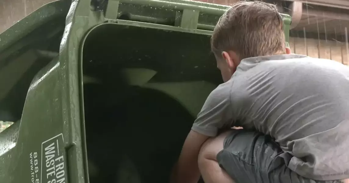 10 year old boy on the clock cleaning trashcans to save money