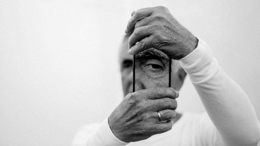 Older male holds phone with enhanced photo of an eye over his left eye